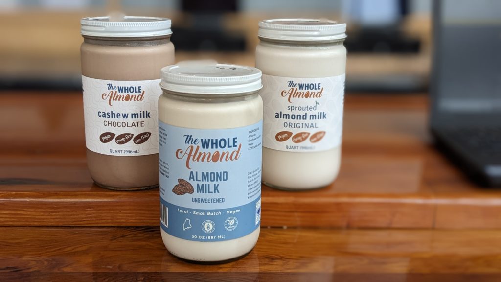 photo of different flavors of almond milk in jars on a wood counter top