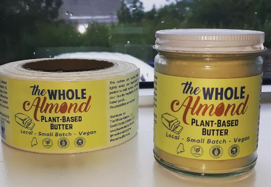 photo of jar of plant-based butter next to a roll of stickers for the jars of butter
