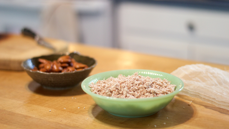 On a wooden block counter, a bowl of shinny almonds and a bowl of rolled oats